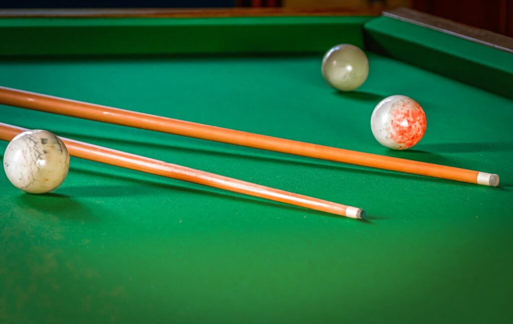 Three cue balls and two cue sticks on a pool table