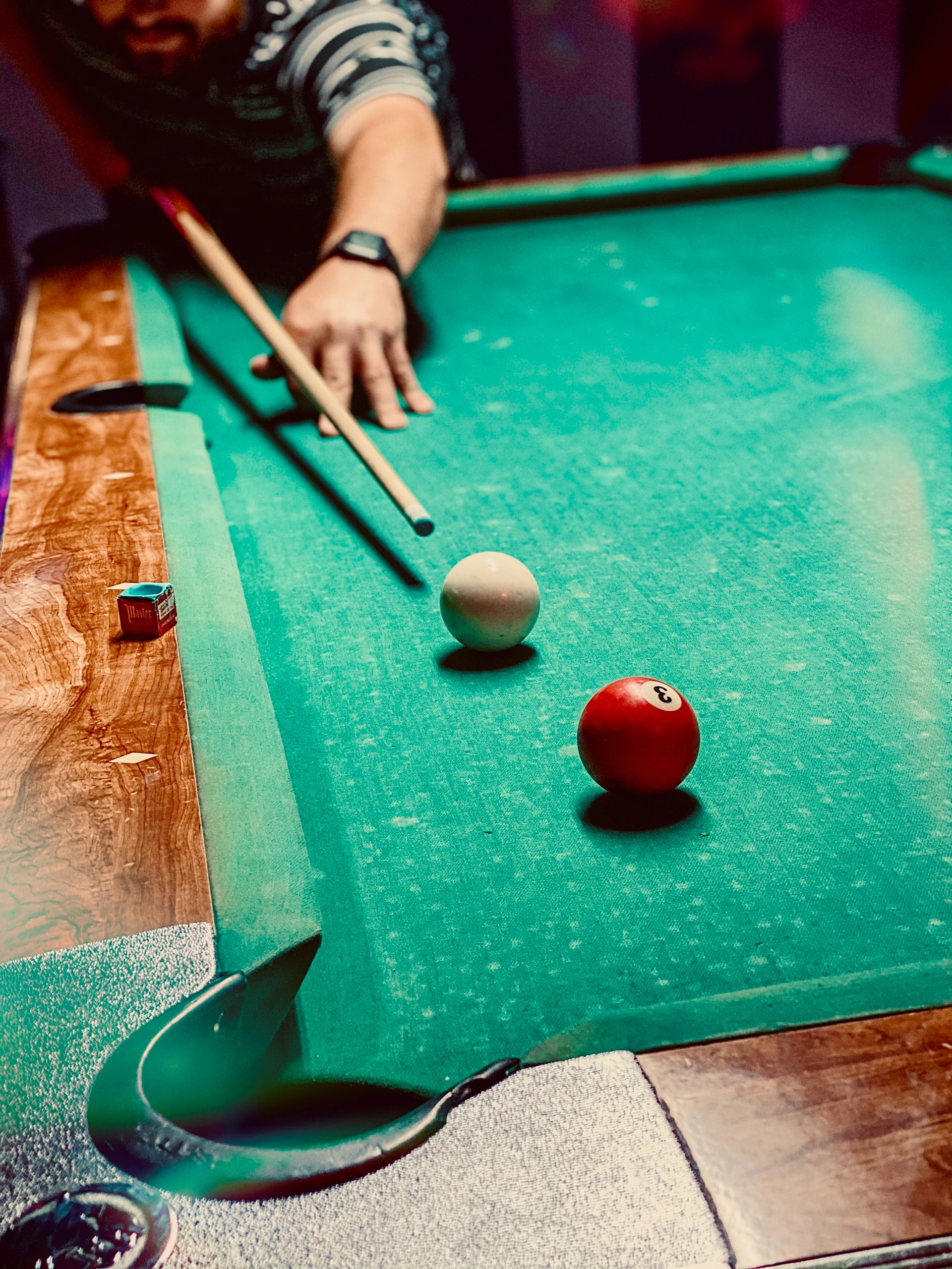 Man getting ready to hit the cue ball with pool cue