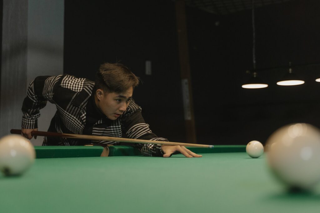 Man wearing a black and white coat playing billiards