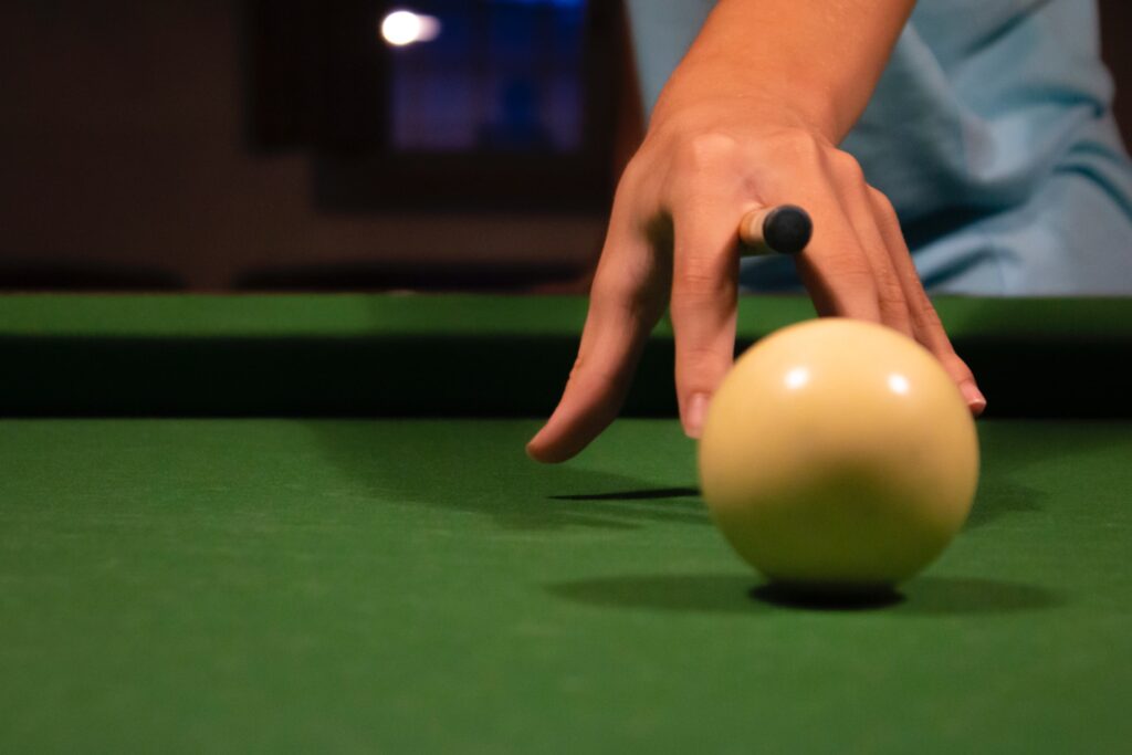 Person pointing a cue stick to the cue ball