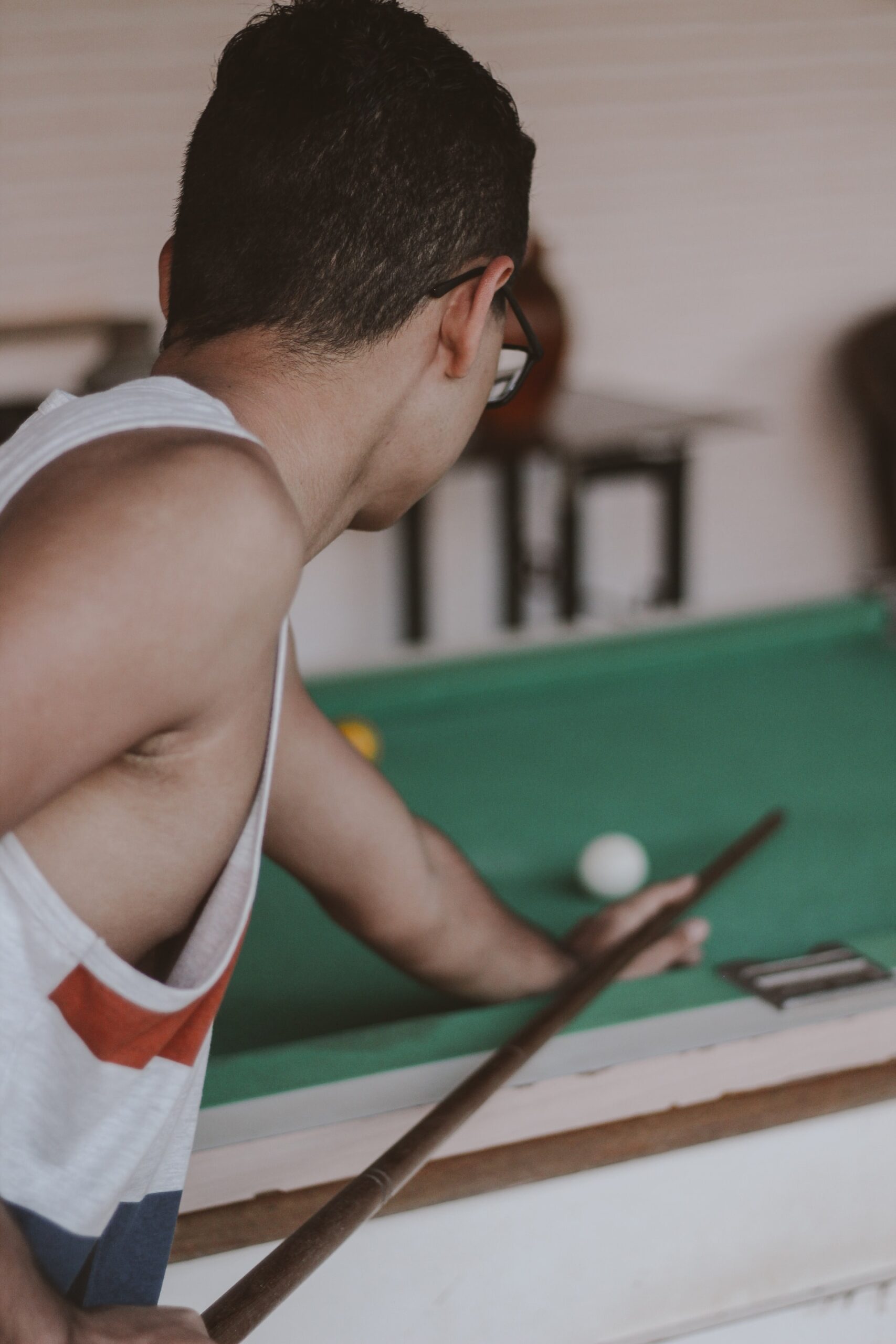 Man in white tank top playing billiards