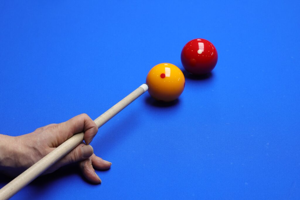 A yellow cue ball and a red ball on a blue billiards table