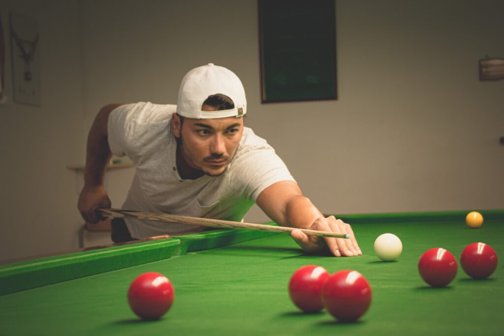 A person playing snooker with red balls