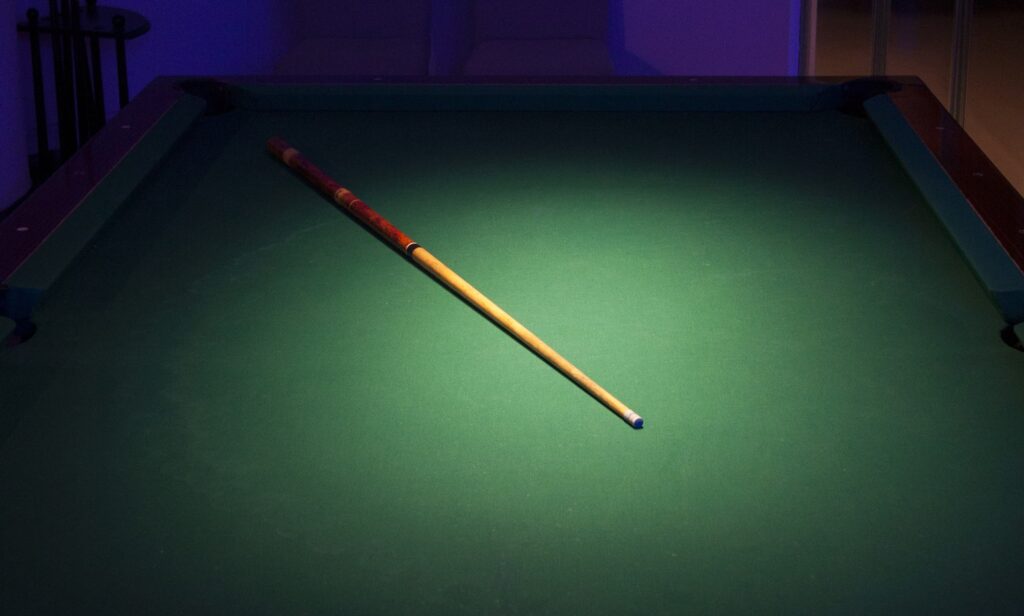 A cue stick on a green billiard table with spotlight