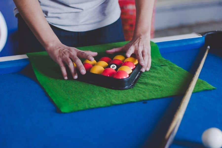 Person arranging the balls in a pool rack