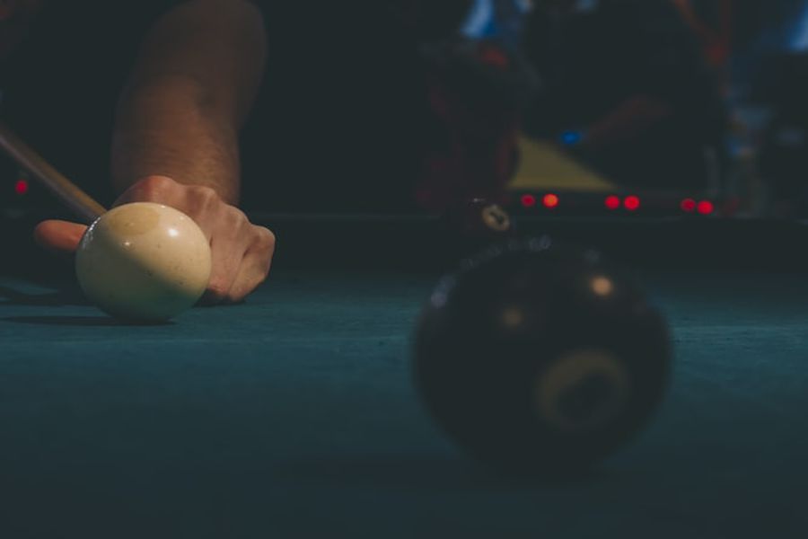 Person aiming the pool cue at a cue ball