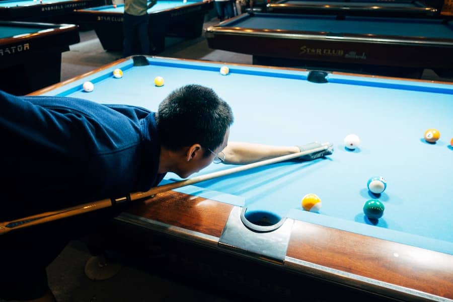 A guy playing billiard with his Mcdermott pool